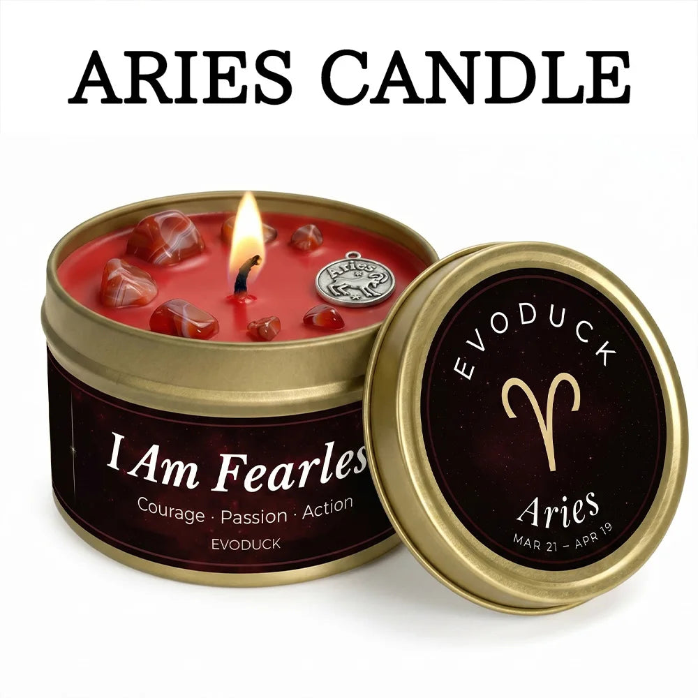 Red Aries zodiac candle in a gold tin, decorated with crystals and an Aries charm, with a lit wick.