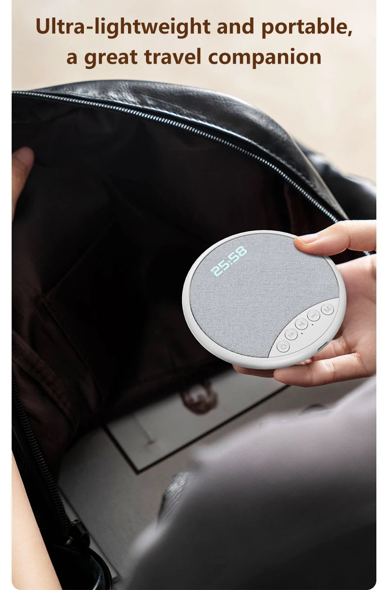 A portable, grey fabric-covered circular speaker with an integrated clock display, being placed into a black bag.