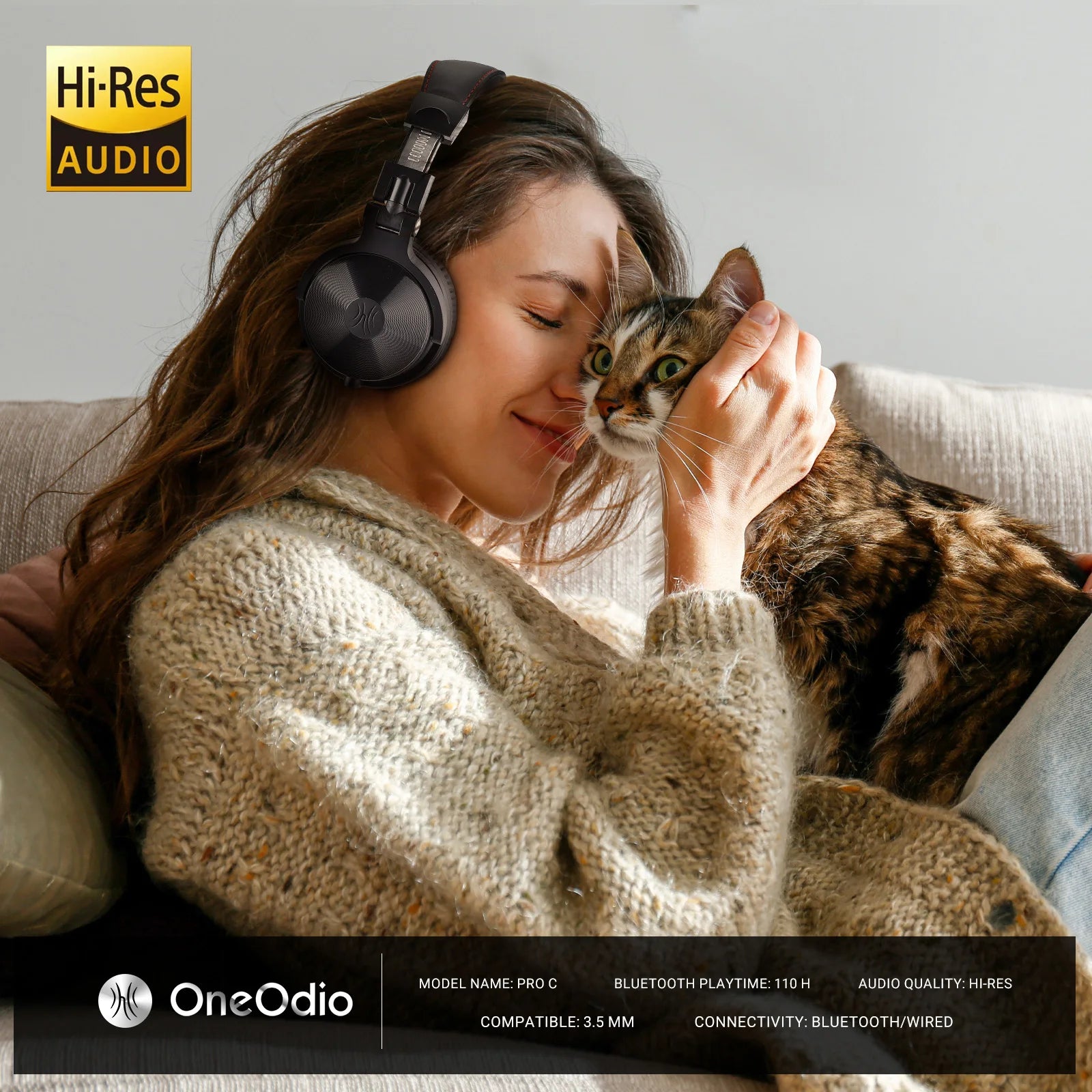 A woman wearing sleek black wireless over-ear headphones, cuddling a cat on a sofa. Hi-Res audio quality.