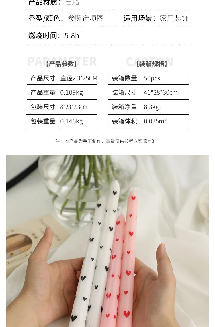 Two white and two light pink tapered dinner candles with small red heart prints, held in hands.
