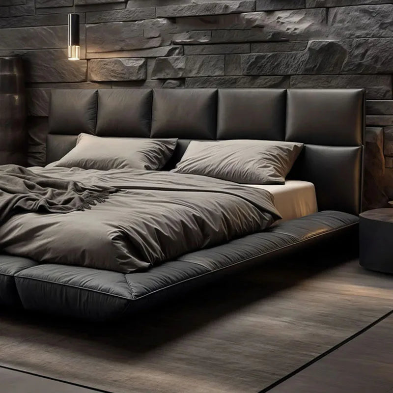 Modern black leather king-size floating bed with a tall, panelled headboard against a dark stone wall.