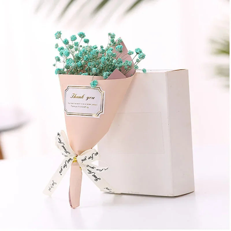 Small bouquet of teal baby’s breath flowers wrapped in pink paper with a 'Thank you' tag and ribbon.