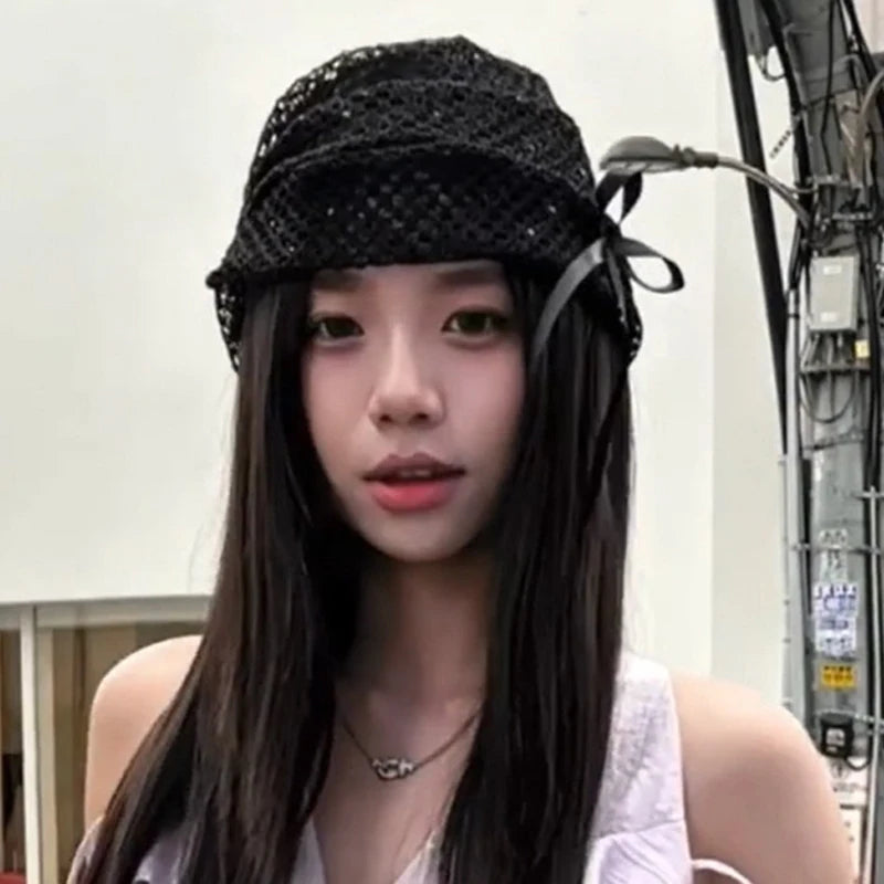 A woman wearing a black, open-knit bucket hat featuring a decorative side bow.