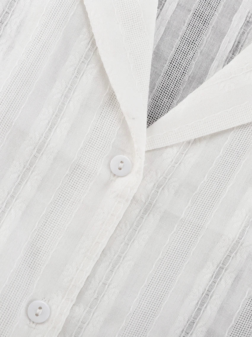 Close-up of a white, textured striped shirt with a collar and matching buttons.