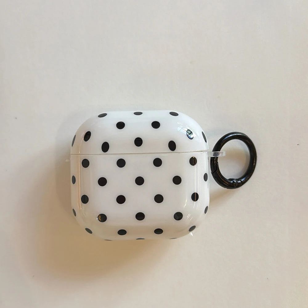 White hard-shell AirPods Pro case with a black polka dot pattern and matching black carabiner keyring.