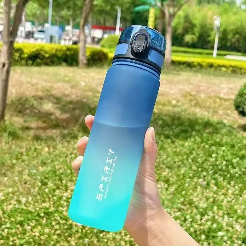 Handheld blue-to-teal ombre water bottle with "SPIRIT" text, a locking lid, and a matte finish, held outdoors.