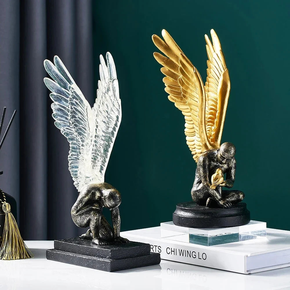 Two decorative angel statues: one with translucent wings and one with metallic gold wings on black bases.