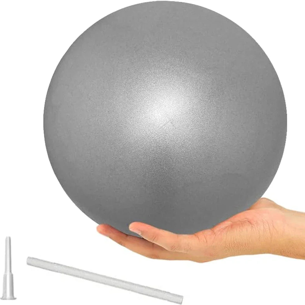 A hand holding a small, smooth grey pilates ball, shown with an inflation straw and nozzle.