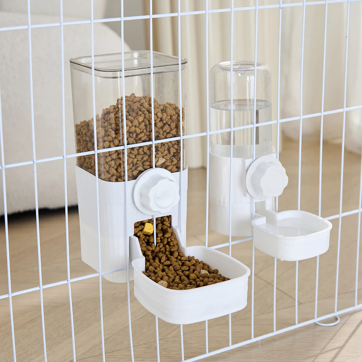 White, wall-mounted pet food and water dispensers with clear containers attached to a wire cage.