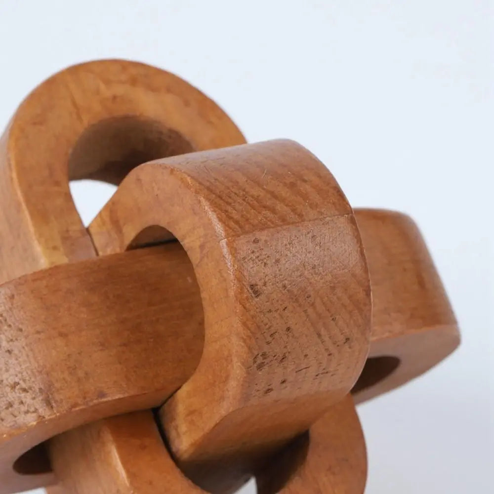 Close-up of a rustic, light brown wooden interlocking puzzle made of smooth, connected curved blocks.