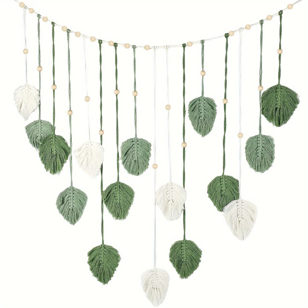 Boho macrame wall hanging featuring sage green and cream leaf motifs on a string with decorative wooden beads.