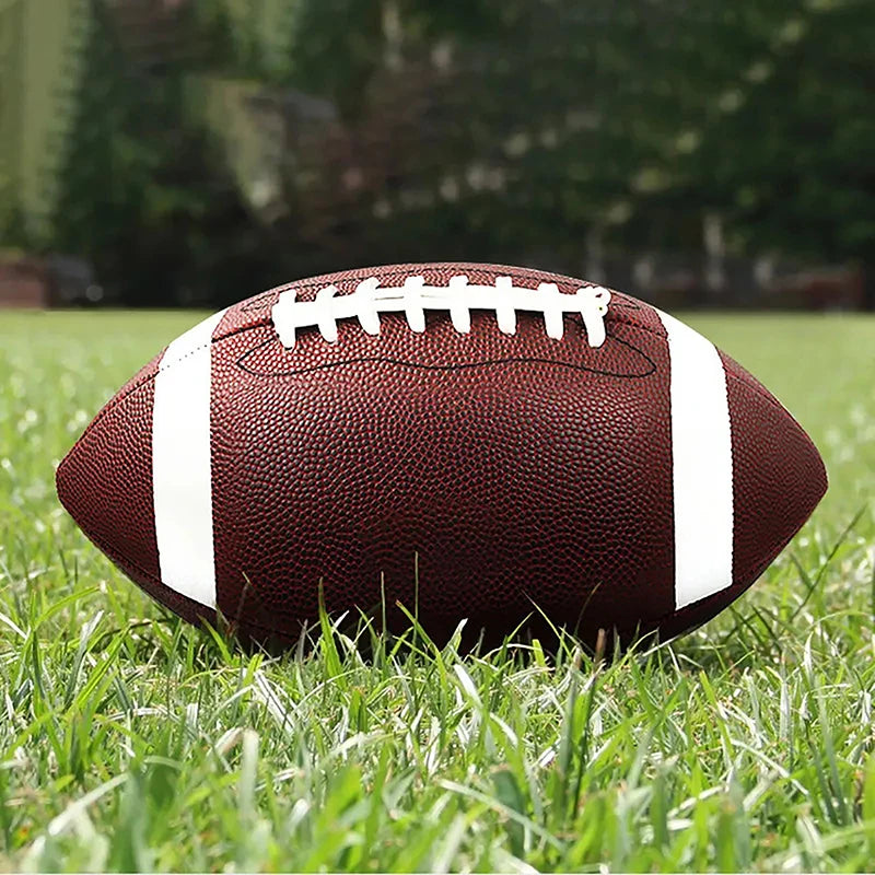 Brown American football with white stripes and laces, resting on green grass.