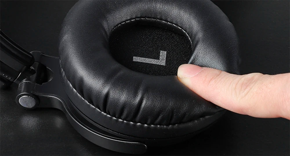 Close-up of a finger pressing into the soft, black, cushioned earcup of an over-ear wireless headphone.