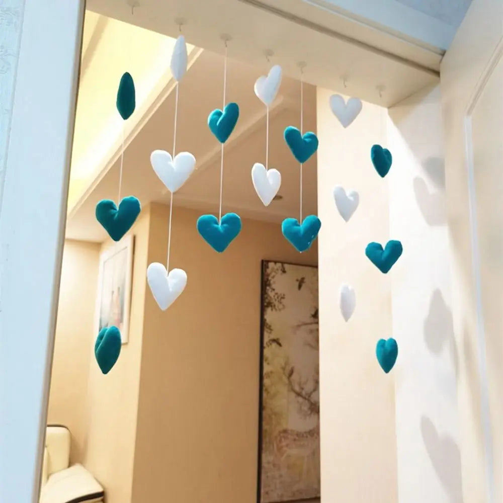 Hanging decorative strings featuring plush teal and white hearts, suspended in a doorway for a charming bedroom accent.