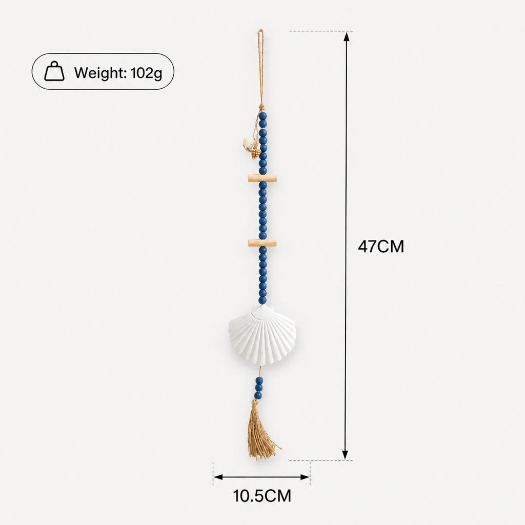 Boho wall hanging with blue wooden beads, light wood accents, a white seashell centrepiece, and a natural fibre tassel.