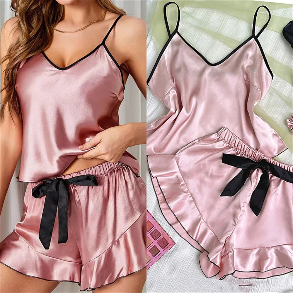 Pink satin camisole and shorts pyjama set with black trim, spaghetti straps, and a black ribbon bow detail.