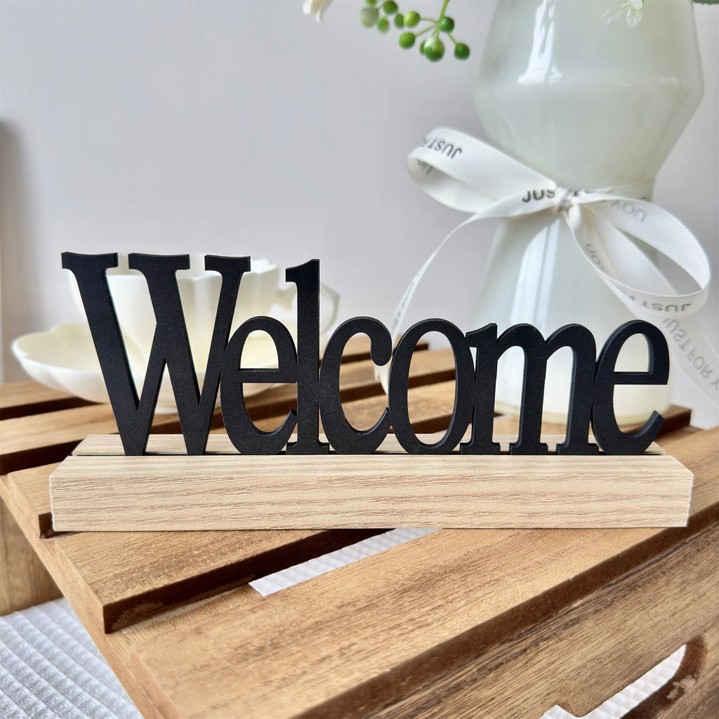 Rustic 'Welcome' sign featuring black wooden lettering on a natural light wood base.
