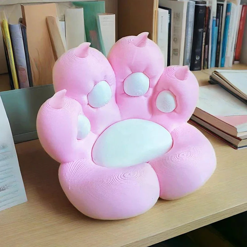 Cute pink and white cat paw-shaped chair with a textured, 3D-printed style surface, resting on a wooden desk.