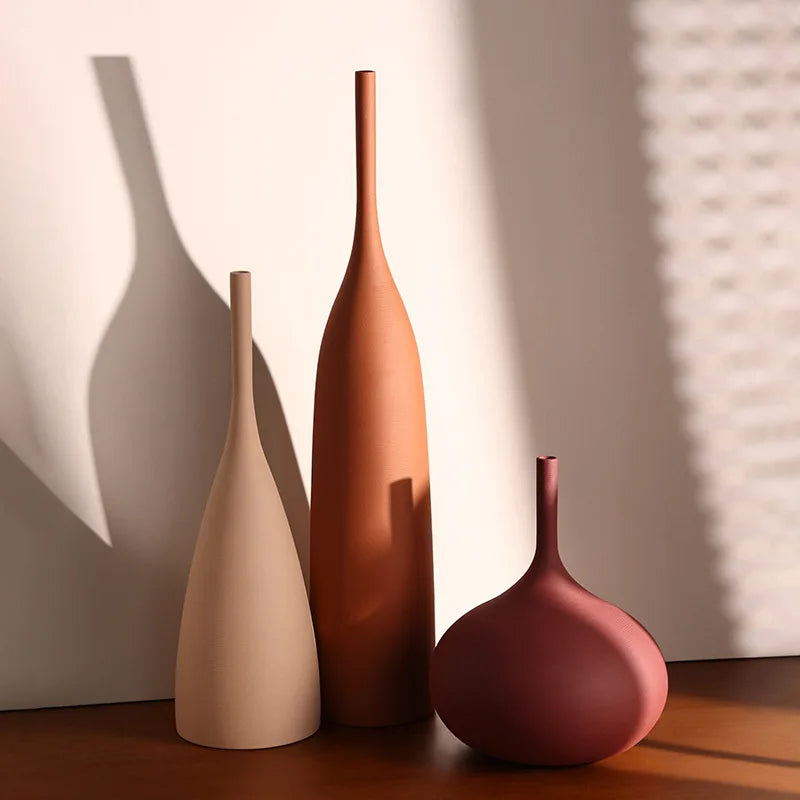 Three handmade ceramic vases in neutral, terracotta, and deep rose with minimalist, wabi-sabi slender designs.