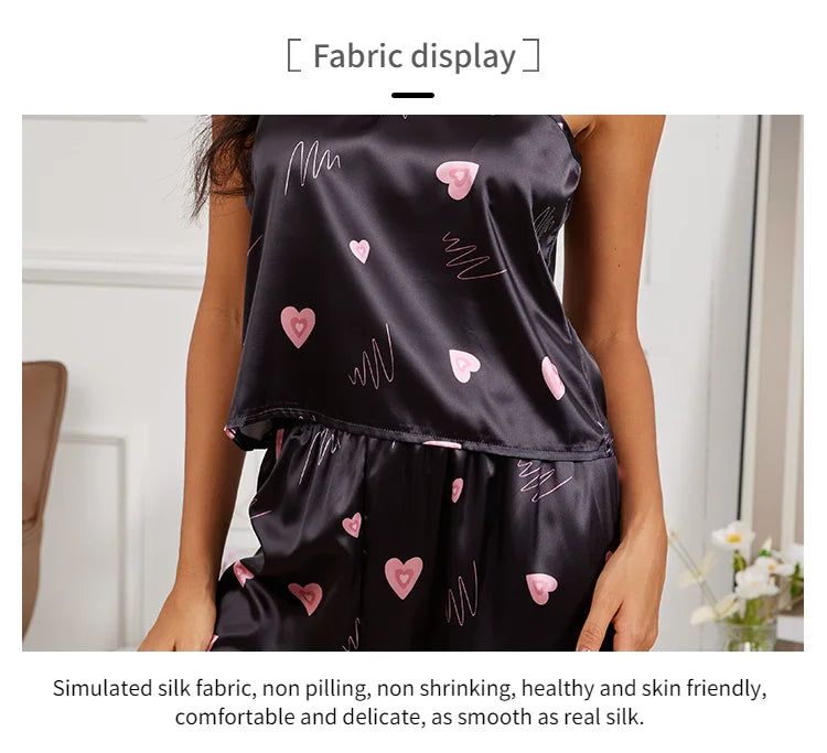 Black satin pajama set with pink heart and scribble print, featuring a camisole top and matching shorts.
