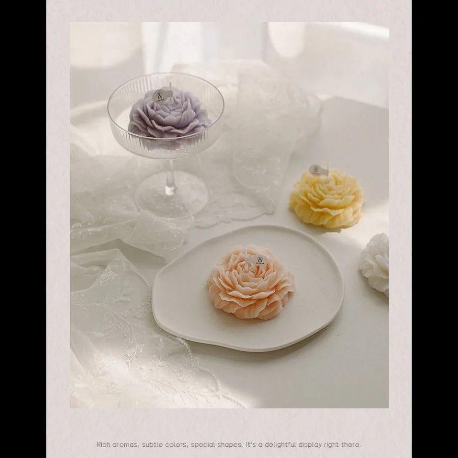 Pastel rose-shaped candles in purple, yellow, peach, and white, displayed on decorative glass and ceramic dishes.