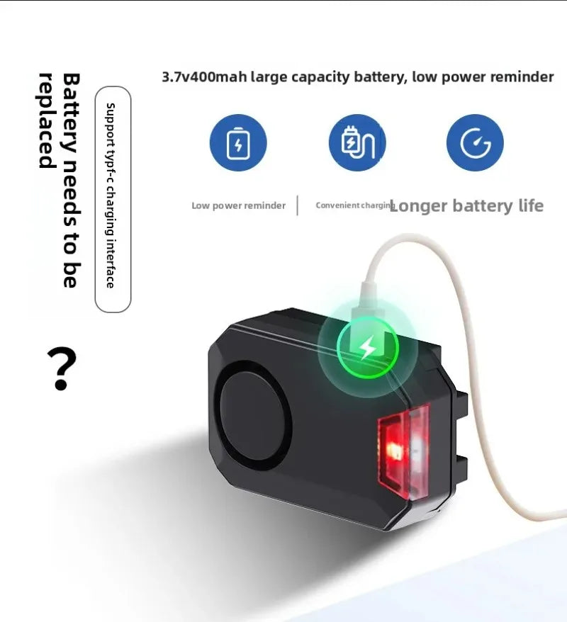 Black plastic electronic alarm device with a USB-C charging port, battery indicator, and a small red LED light.