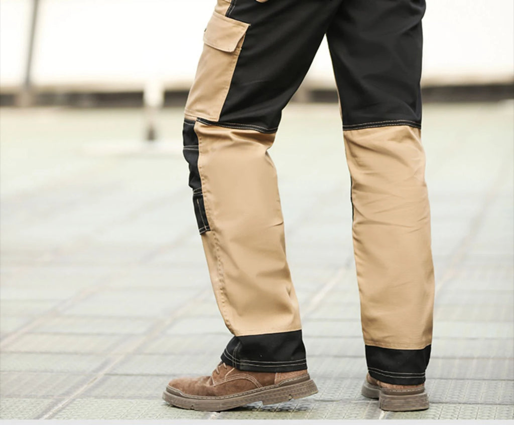 Men's black and beige cargo work trousers with side pockets and durable stitch detailing, worn with brown boots.