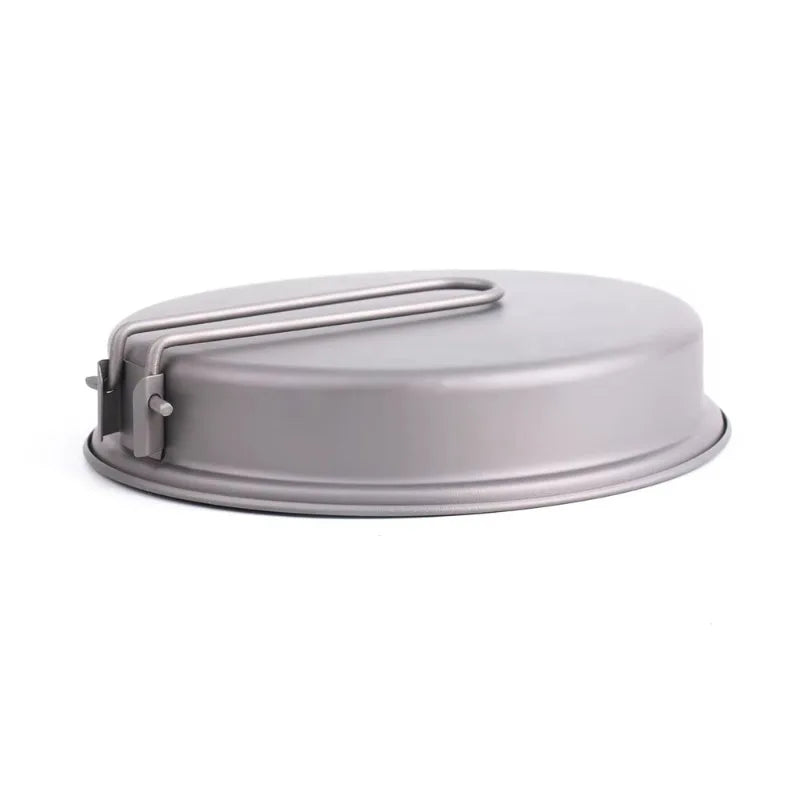 A round, grey metal pan with a folding wire handle on its side, viewed on a white background.