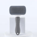 Grey and white self-cleaning slicker brush for pets with a textured, ergonomic handle, standing on a white pedestal.