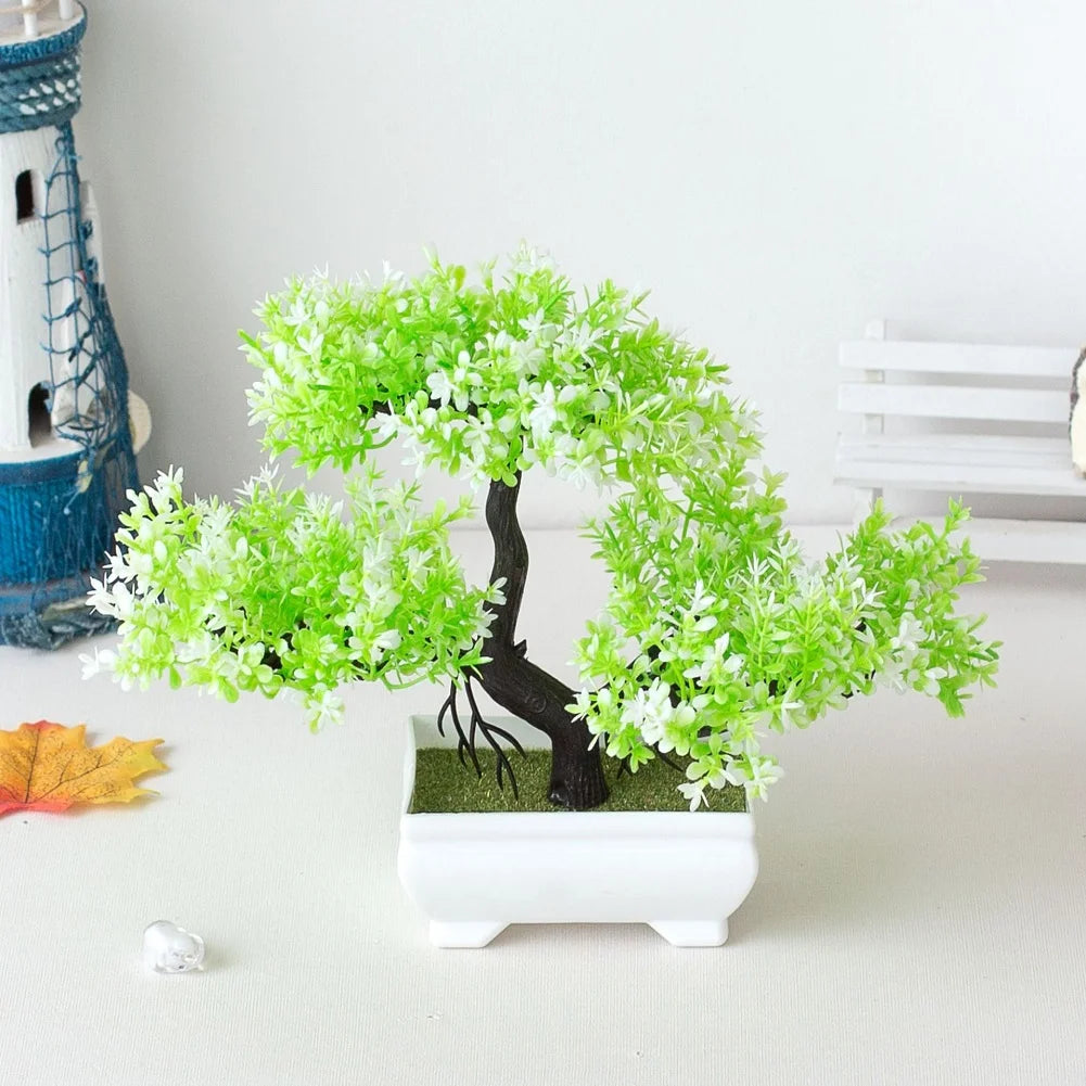 Small artificial bonsai tree with bright green foliage in a rectangular white ceramic pot on a white tabletop.