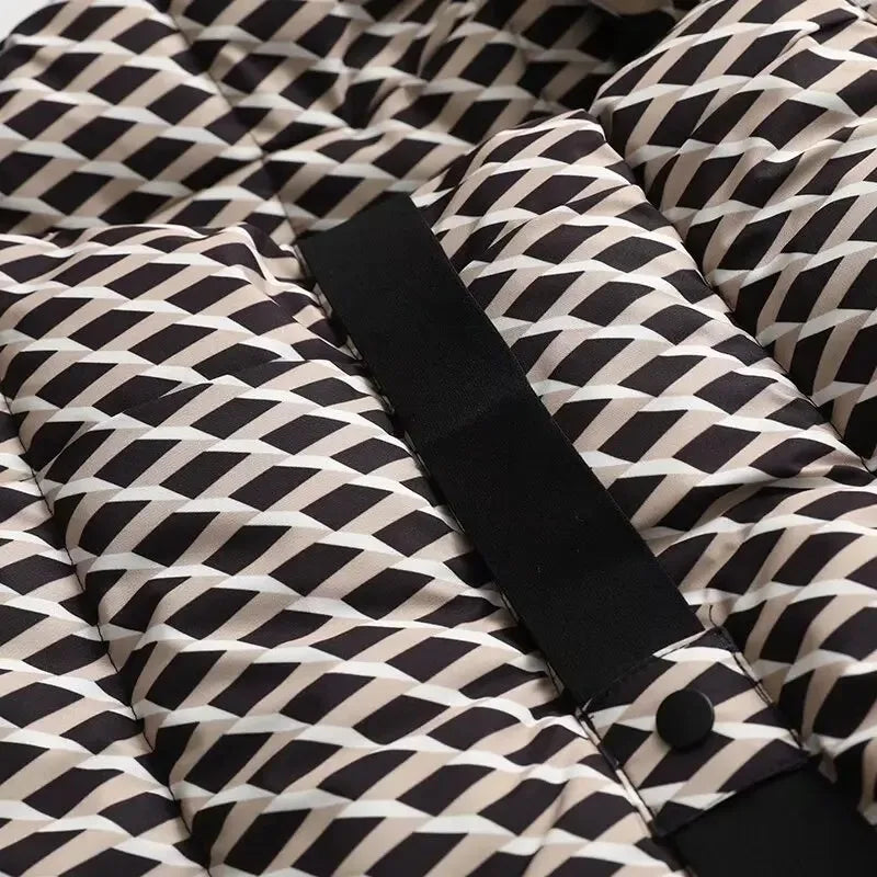 Close-up of a quilted puffer jacket in black, beige, and white geometric diamond pattern with a black snap-button strap.