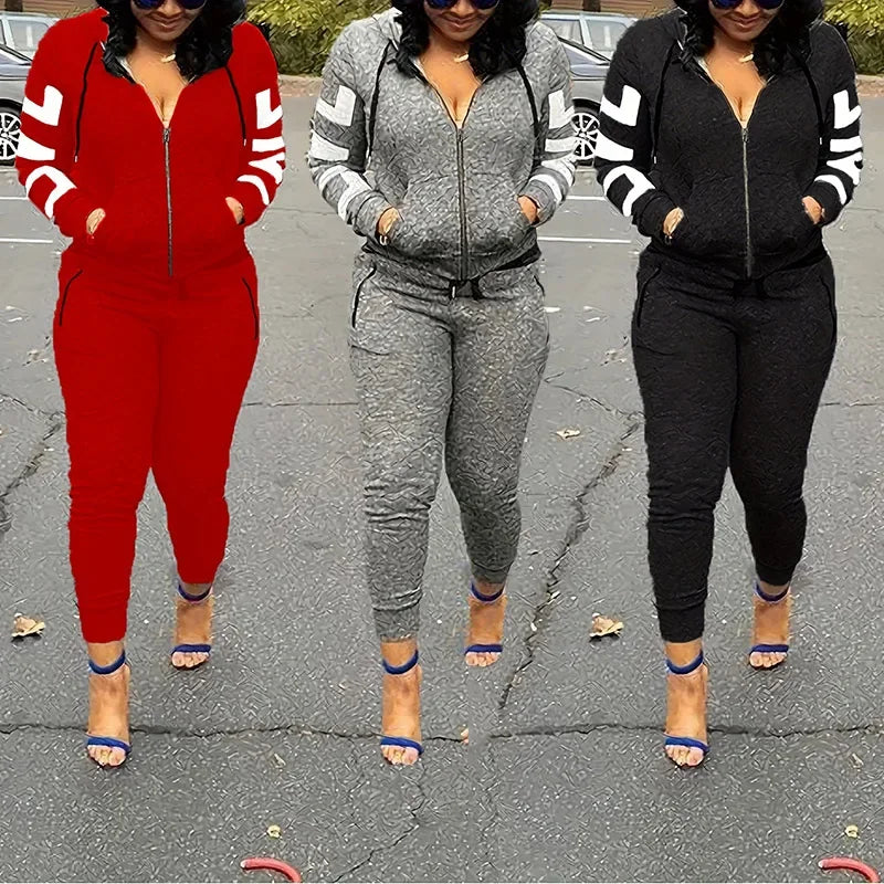 Three women wearing zip-up hooded tracksuit sets in red, grey, and black, featuring white striped sleeves.