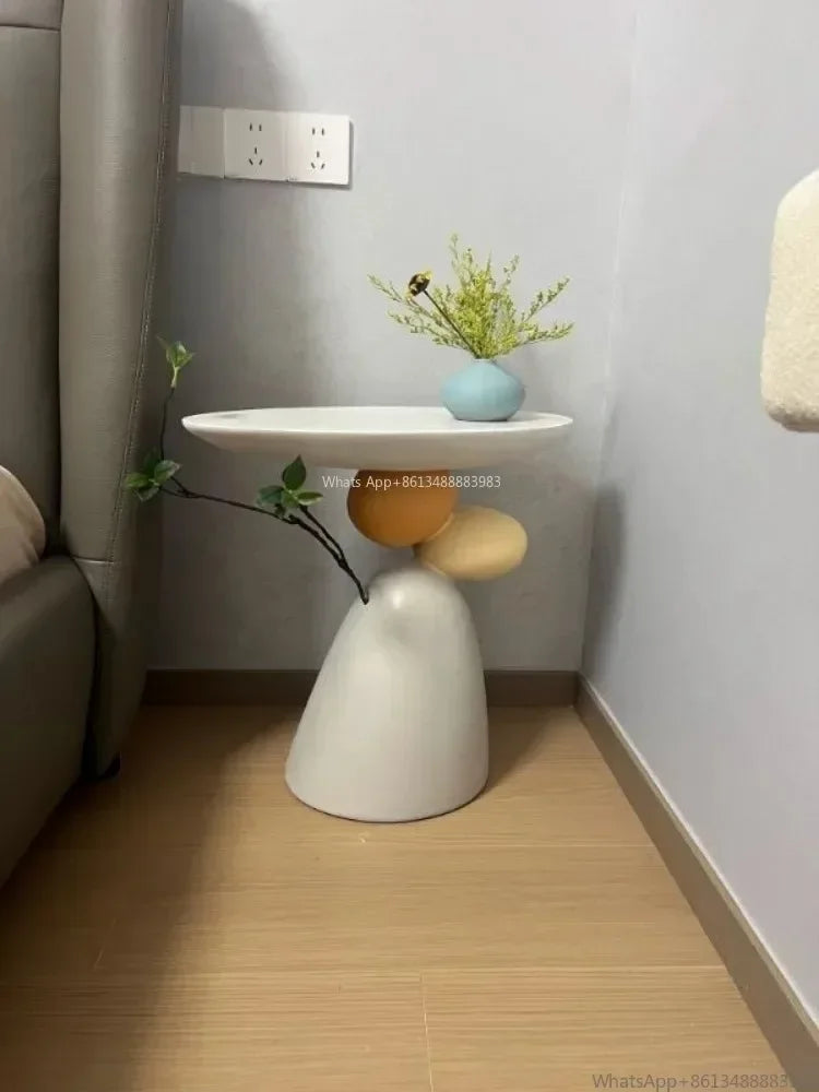 Minimalist cream-coloured side table with a unique stacked pebble-shaped base and a smooth round tabletop.