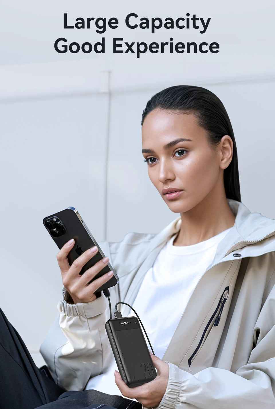 A woman holds a sleek black 20,000mAh portable power bank with an LED indicator, charging her smartphone via cable.