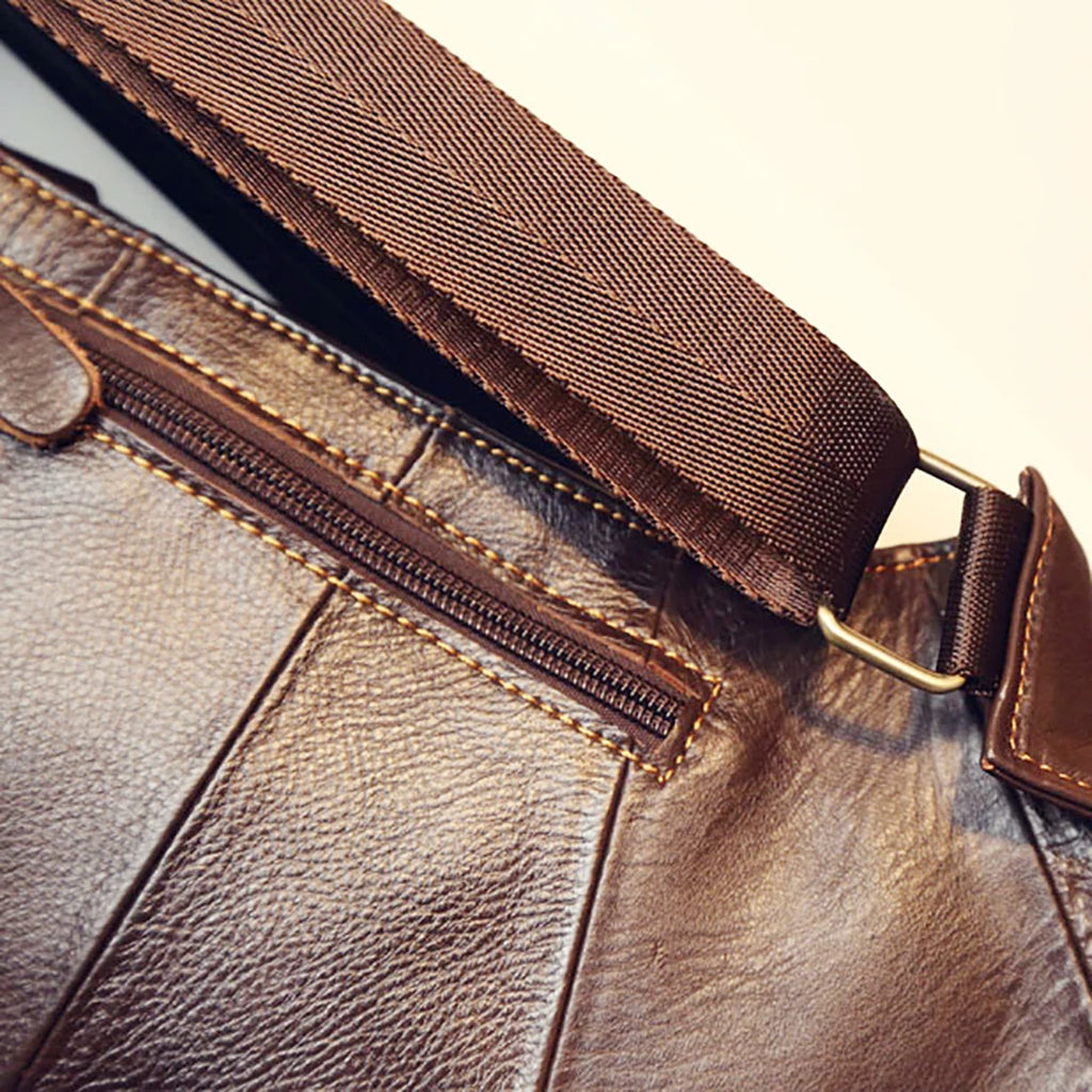 Close-up of a brown leather men's crossbody bag featuring contrast stitching, a zip pocket and an adjustable strap.