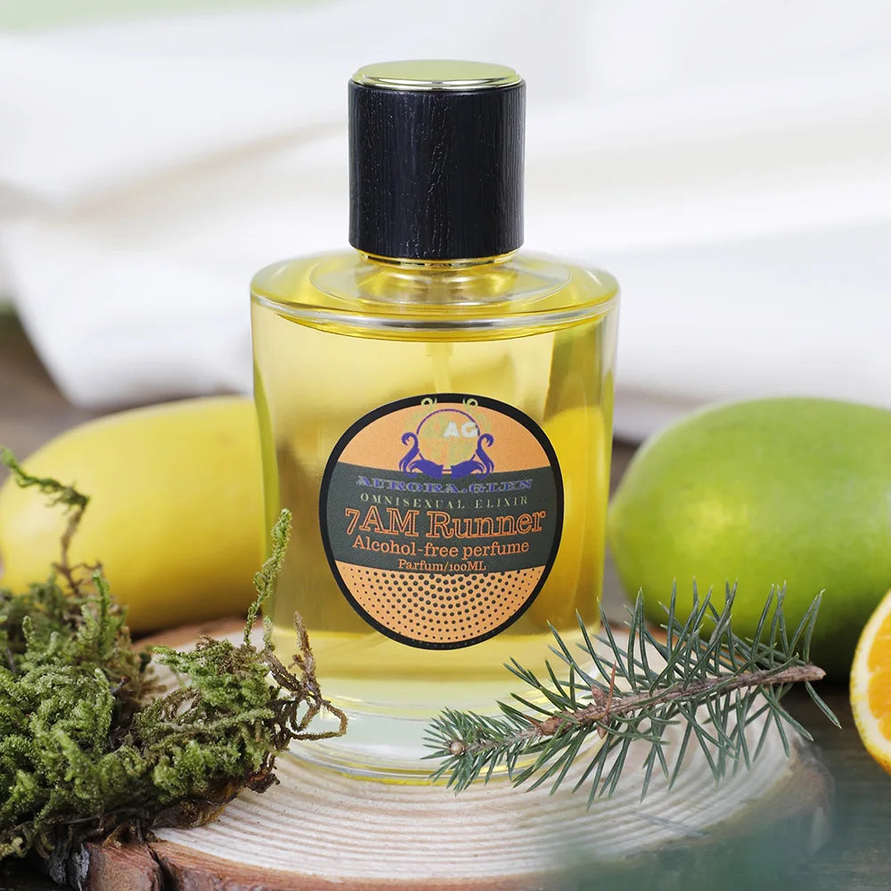 A 100ml bottle of yellow alcohol-free perfume with a black cap, displayed with fresh citrus, pine, and moss.