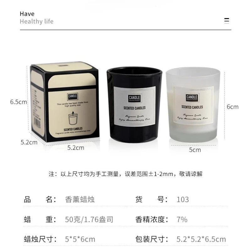 Two scented candles in black and frosted glass jars, each with a label, shown alongside their matching box.