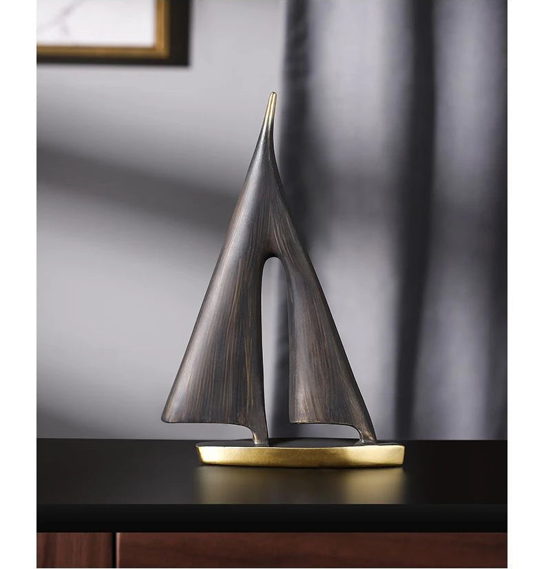 Abstract sailboat ornament in dark, textured bronze-effect resin with a smooth, brushed gold-coloured base.
