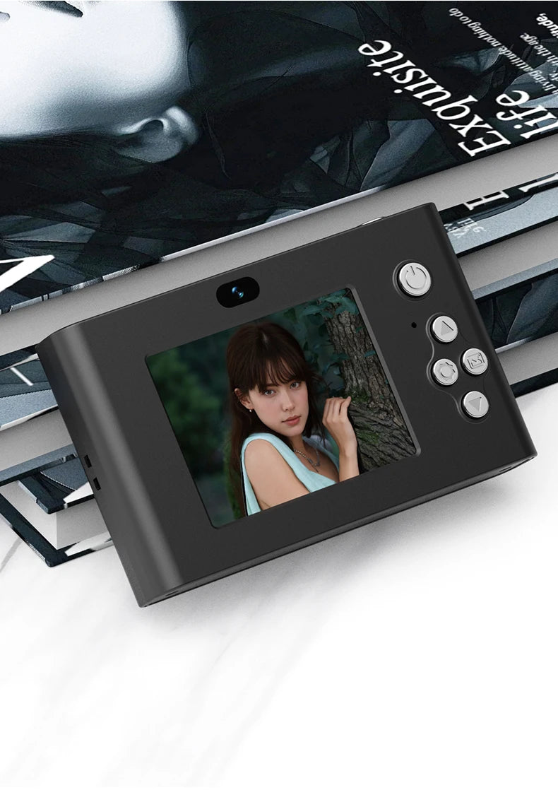 Black matte digital instant camera with a screen displaying a person, front-facing buttons, and camera lens.
