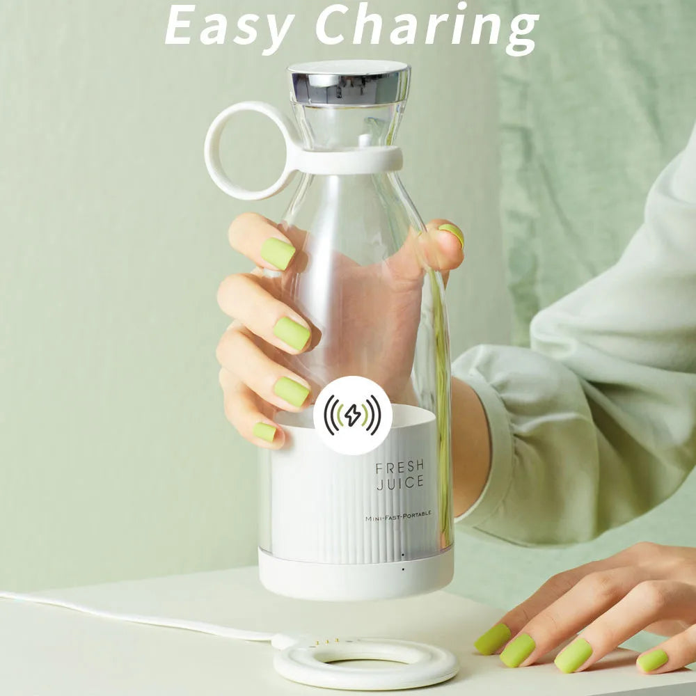 Portable white electric blender bottle with a transparent body and wireless magnetic charging base.