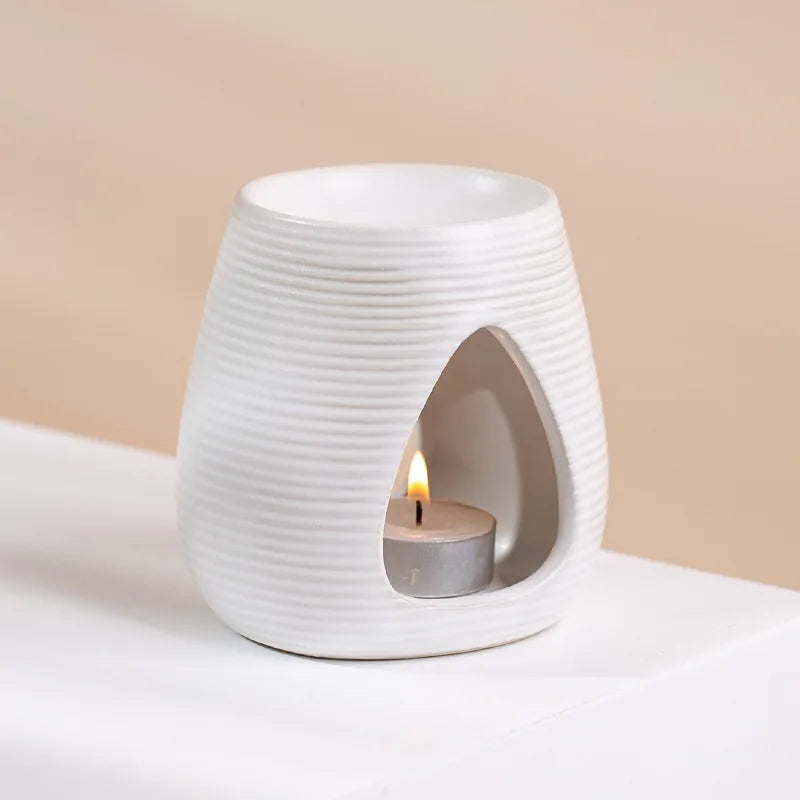 White ceramic wax melt burner with a textured, ribbed finish and a teardrop-shaped opening for a tea light candle.