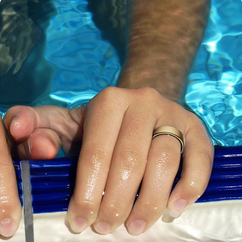 A sleek, gold-coloured waterproof smart health ring worn on a finger while in a swimming pool.