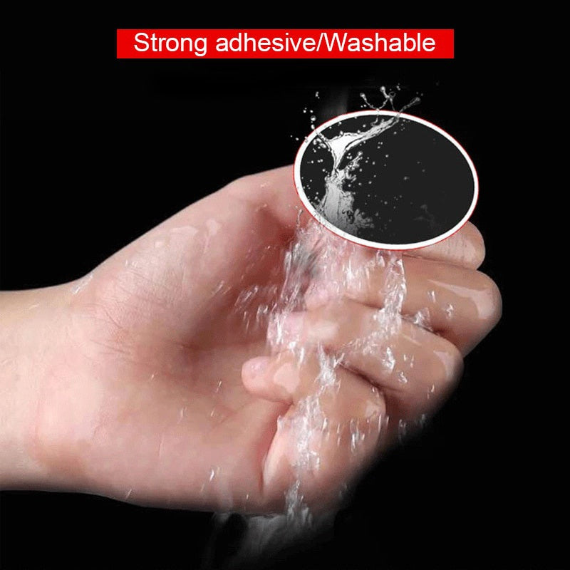 A small, circular black adhesive pad being rinsed under a stream of water, highlighting its washable design.