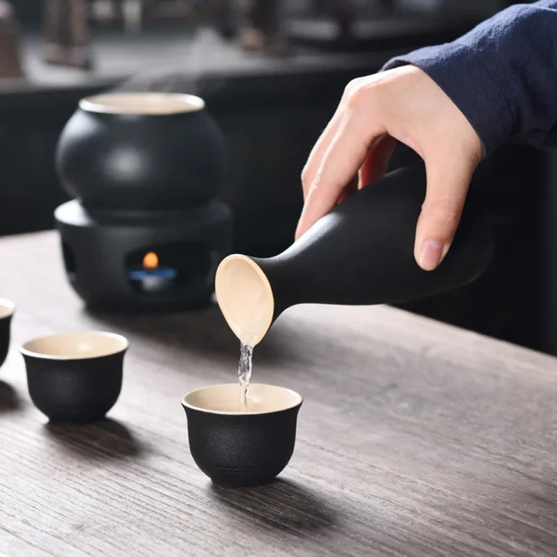 Black ceramic sake set featuring a pouring bottle, small cups, and a candle warmer.