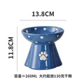 Blue ceramic elevated cat bowl with white polka dots and a paw print design. Dimensions: 13.8cm wide, 11.8cm high.