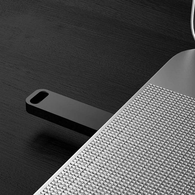 Sleek, black metal USB flash drive with a lanyard hole, plugged into a silver laptop with a textured surface.