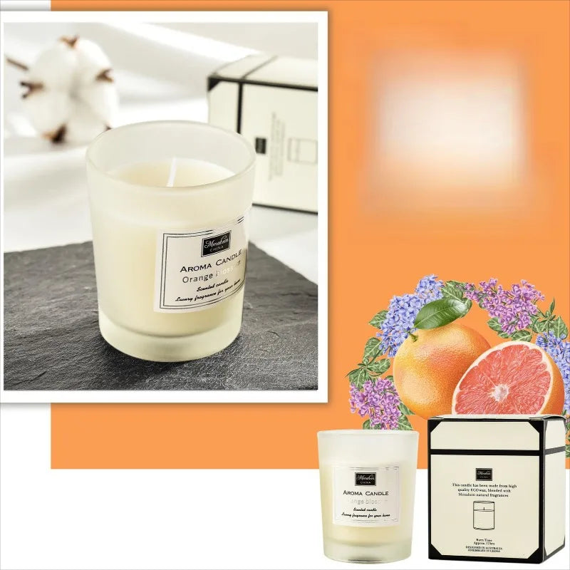 Scented candle in a frosted glass jar with label, featuring orange and floral accents, presented with its gift box.