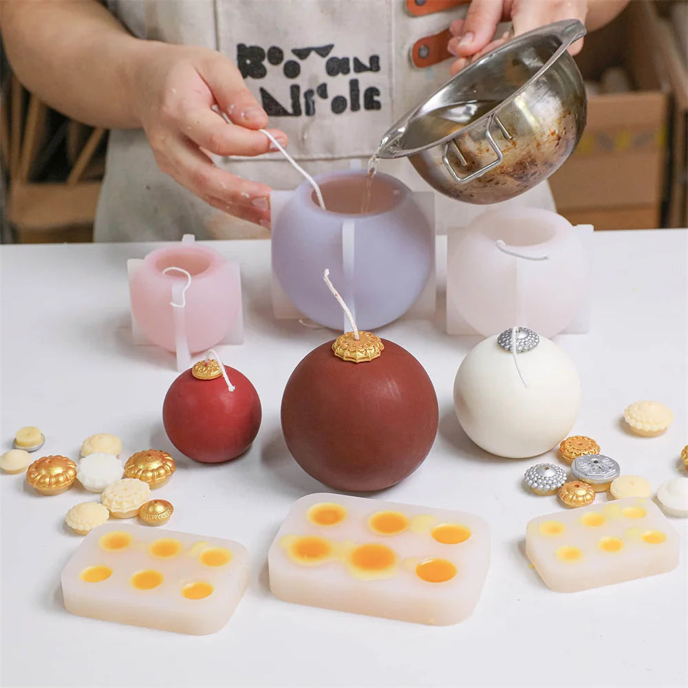 Silicone candle molds and finished spherical Christmas bauble candles in red, brown, and white with gold caps.