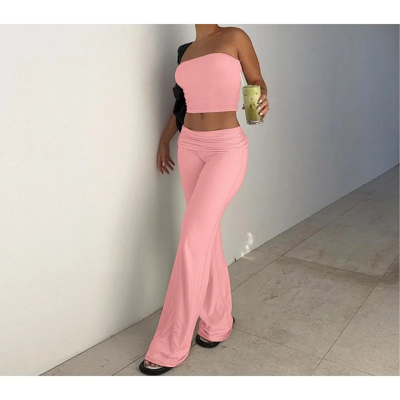 Model wearing a baby pink co-ord set with a strapless crop top and high-waisted, wide-leg flared trousers.