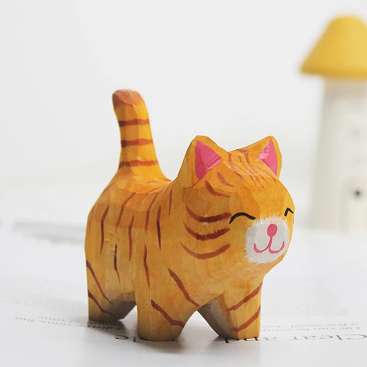 Small hand-carved wooden orange tabby cat figurine with a cute, happy expression and upright tail.
